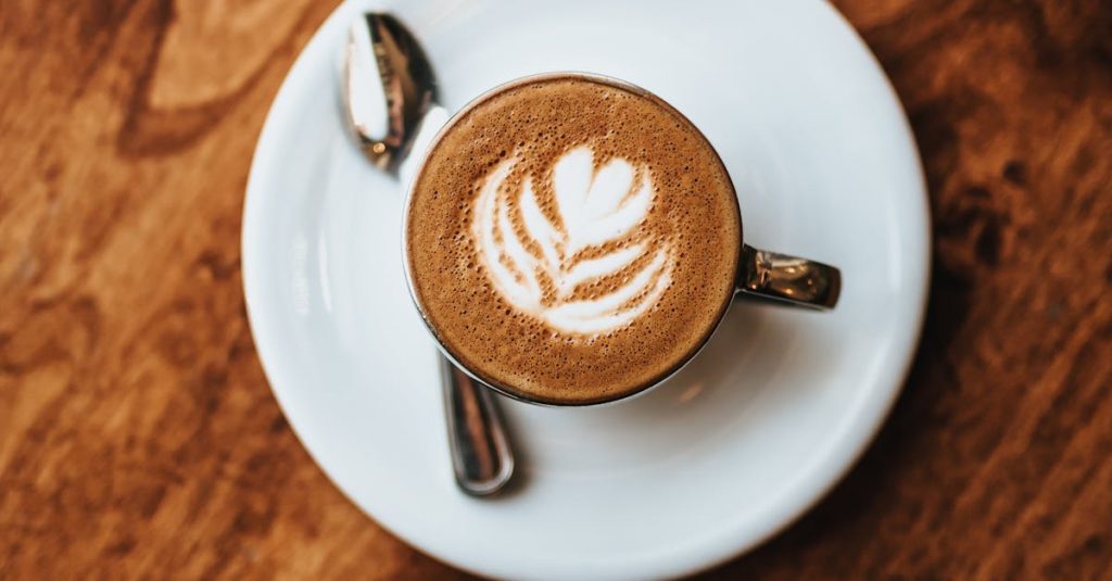 A top-down view of cappuccino with latte art, placed on a rustic wooden table.