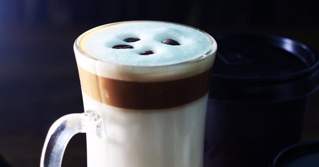 A stylish glass mug of latte with foam art, surrounded by coffee beans, adds a touch of elegance.